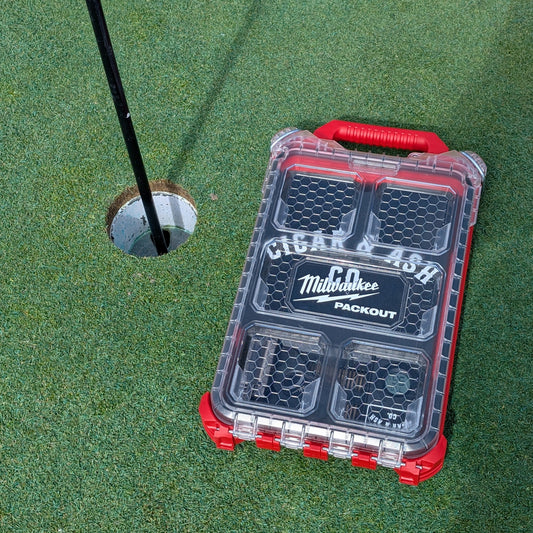 Milwaukee Packout 48-22-8436 case with Packidor humidor insert sitting next to golf hole on putting green